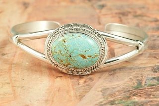 Genuine Number 8 Mine Turquoise Stone set in heavy gauge Sterling Silver Bracelet. Created by Navajo Artist John Nelson. Signed by the artist. The Number 8 mine is located in Eureka County Nevada. Since 1976 there has been no Number 8 Turquoise mined. There is however, an existing stock pile that Mr. Dowell Ward, the last owner of the Number 8 mine, had stocked away for later sorting. The Turquoise is a collector's item--because once the reserve is gone there will be no more material released onto the market. The Gold Mining Company owns the claim to the Number 8 mine and it has been swallowed up by the gold mining operations. This is some of the last Number 8 Turquoise to be had and will be a great addition to your collection. 